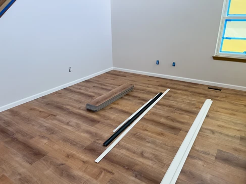 Homme à genoux installant un revêtement de sol en liège dans un intérieur résidentiel