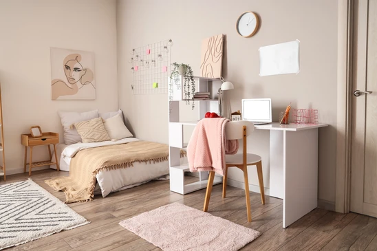 Main posant une plinthe en bois contre un mur blanc sur parquet stratifié