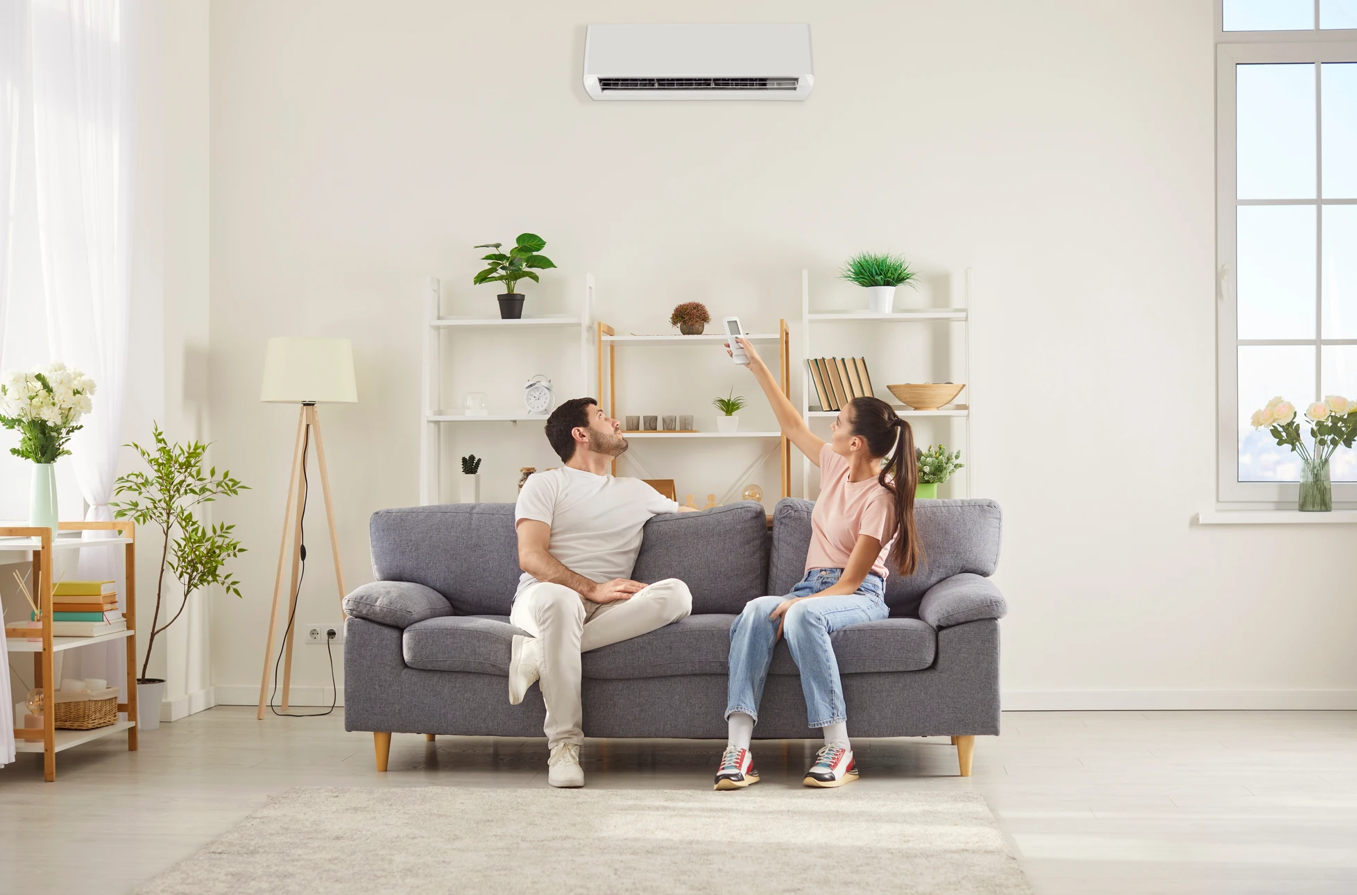 Intérieur moderne avec système de climatisation split comprenant unité extérieure compresseur et unité intérieure murale blanches, accompagnées d'une télécommande infrarouge affichant 24°C