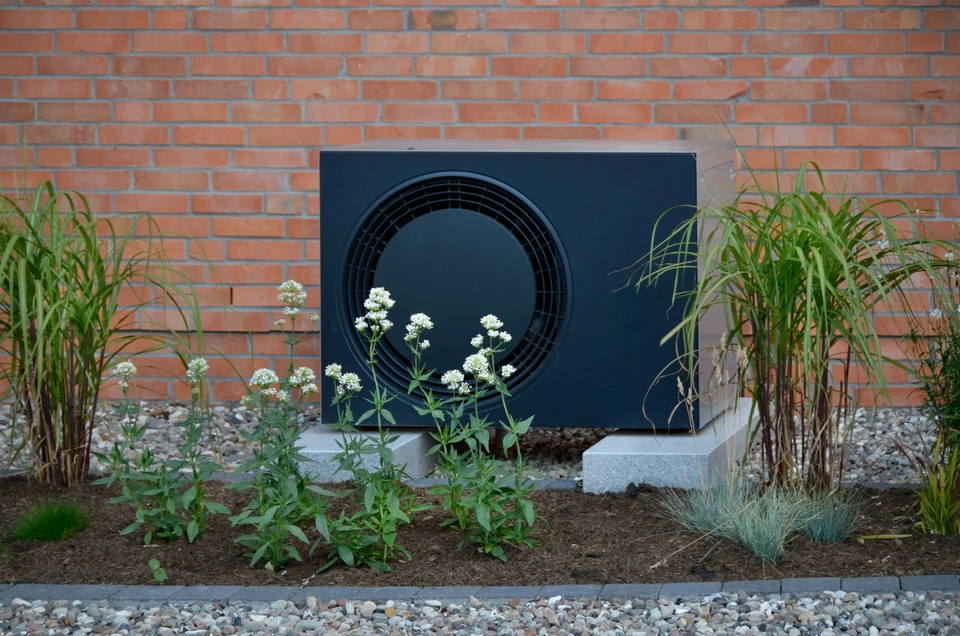 Intérieur moderne avec système de climatisation split composé d'une unité extérieure compacte blanche avec ventilateur bleu et grilles d'aération, unité intérieure murale avec affichage digital et évacuation d'air, télécommande avec écran LCD affichant 24°C