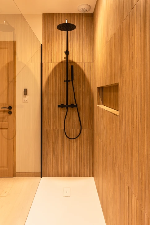 Artisan plombier en salopette rouge travaillant dans une salle de bain moderne blanche